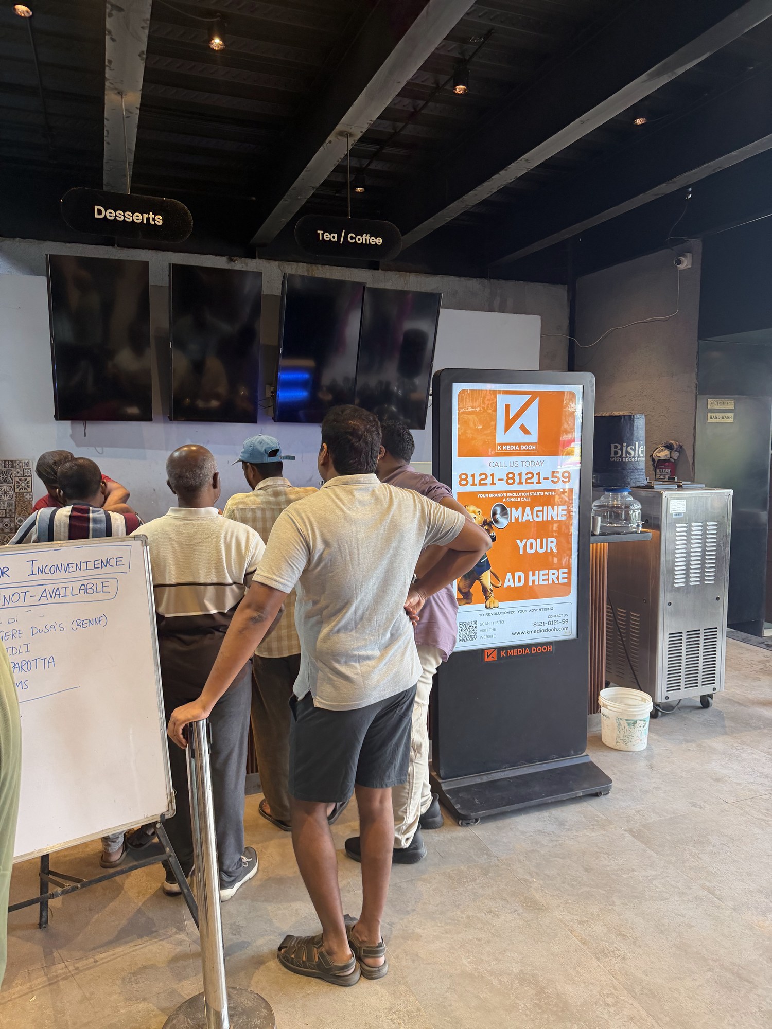KMEDIA digital standee running a live ad campaign beside a restaurant ordering counter