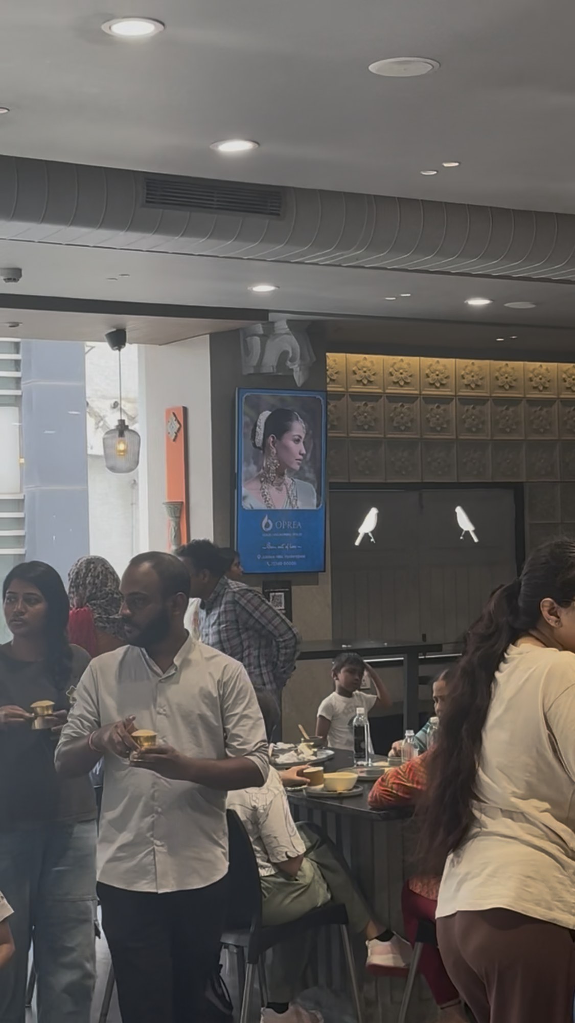 Oprea jewellery campaign on KMEDIA vertical screen in a busy cafe