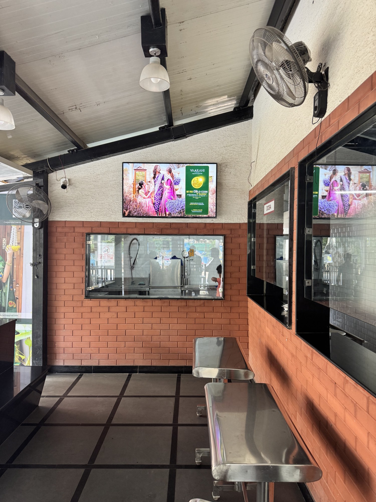 Vaarahi Silks gold coin offer on KMEDIA screen at a cafe service counter